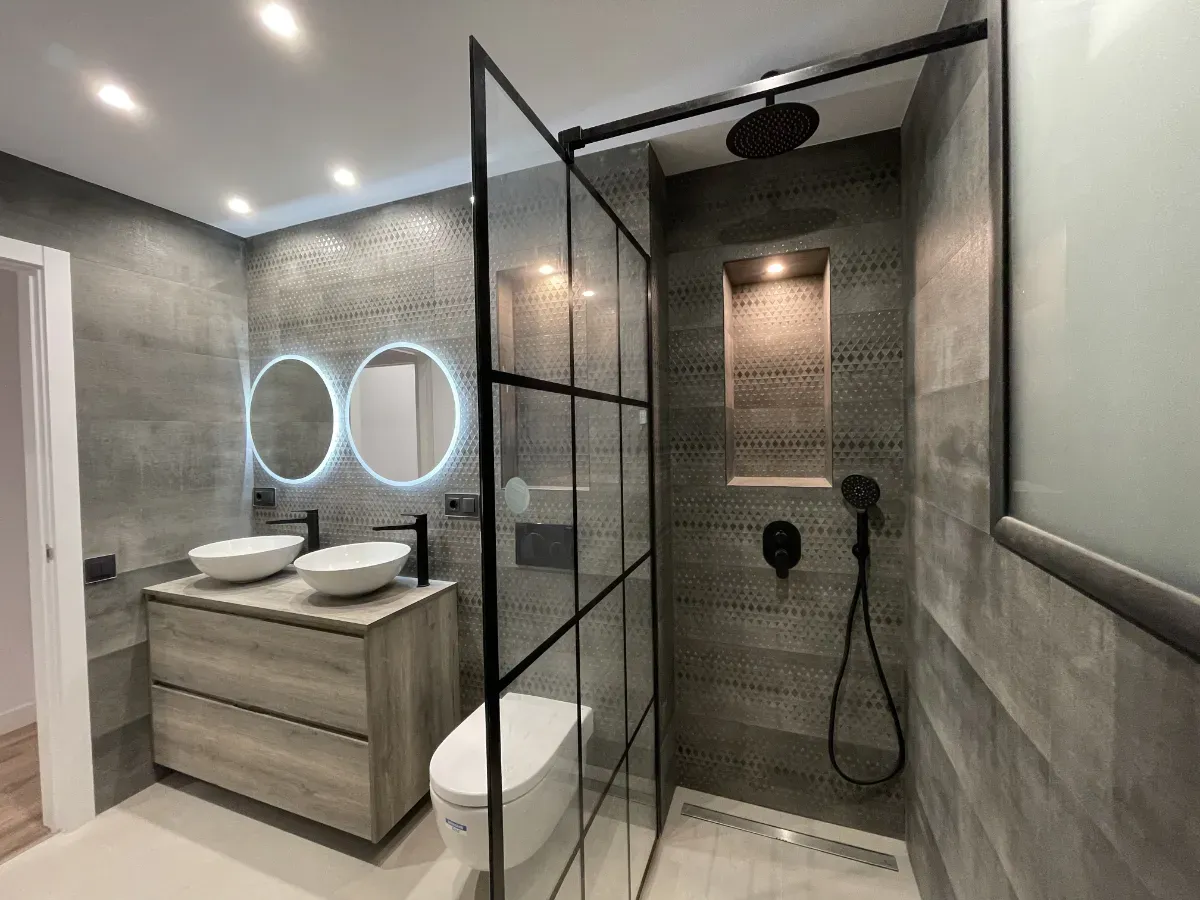 Elegante baño principal reformado con doble lavabo tipo bol, espejos retroiluminados y gran plato de ducha.