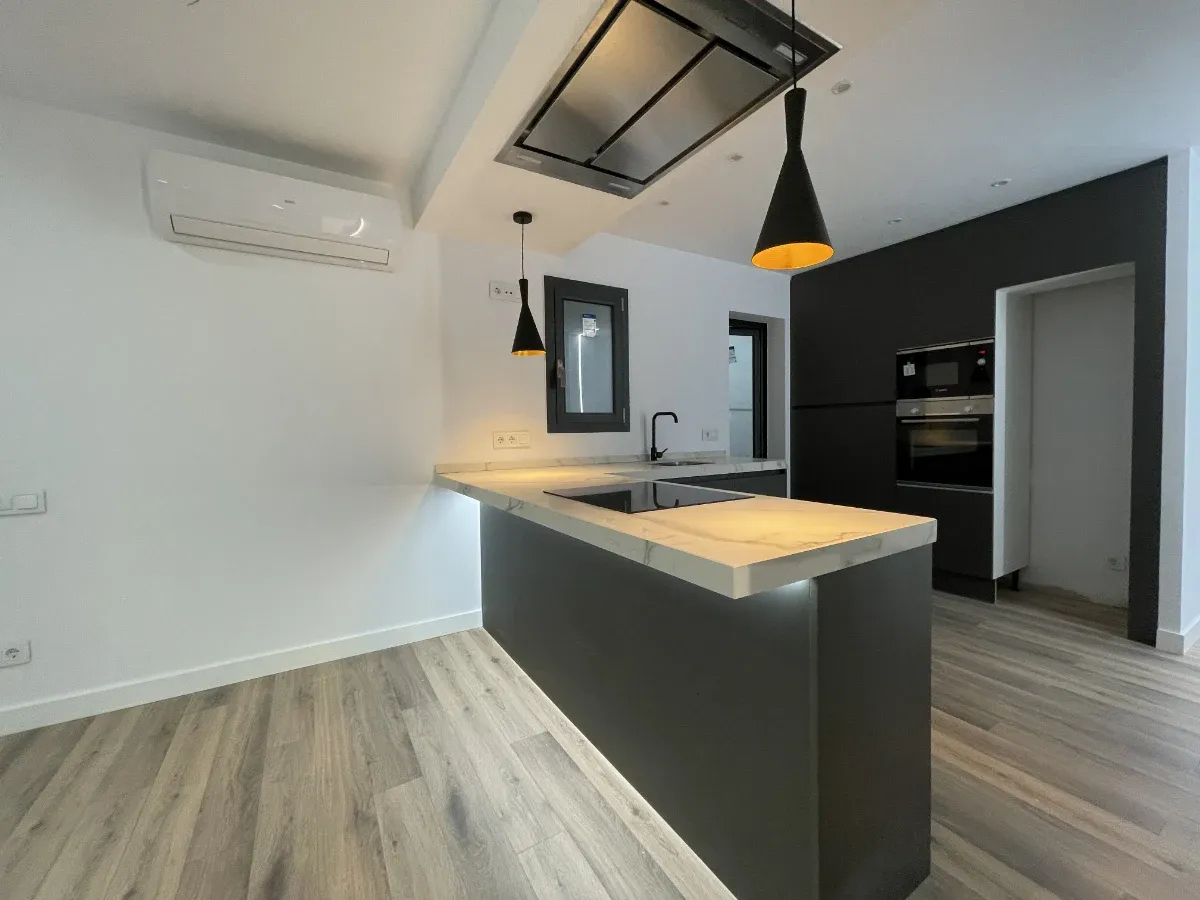 reforma integral de piso en Horta Guinardó - Calle Granollers - Barcelona - detalle de cocina abierta con su peninsula extractor de ultima generación e iluminación con lámparas colgantes 