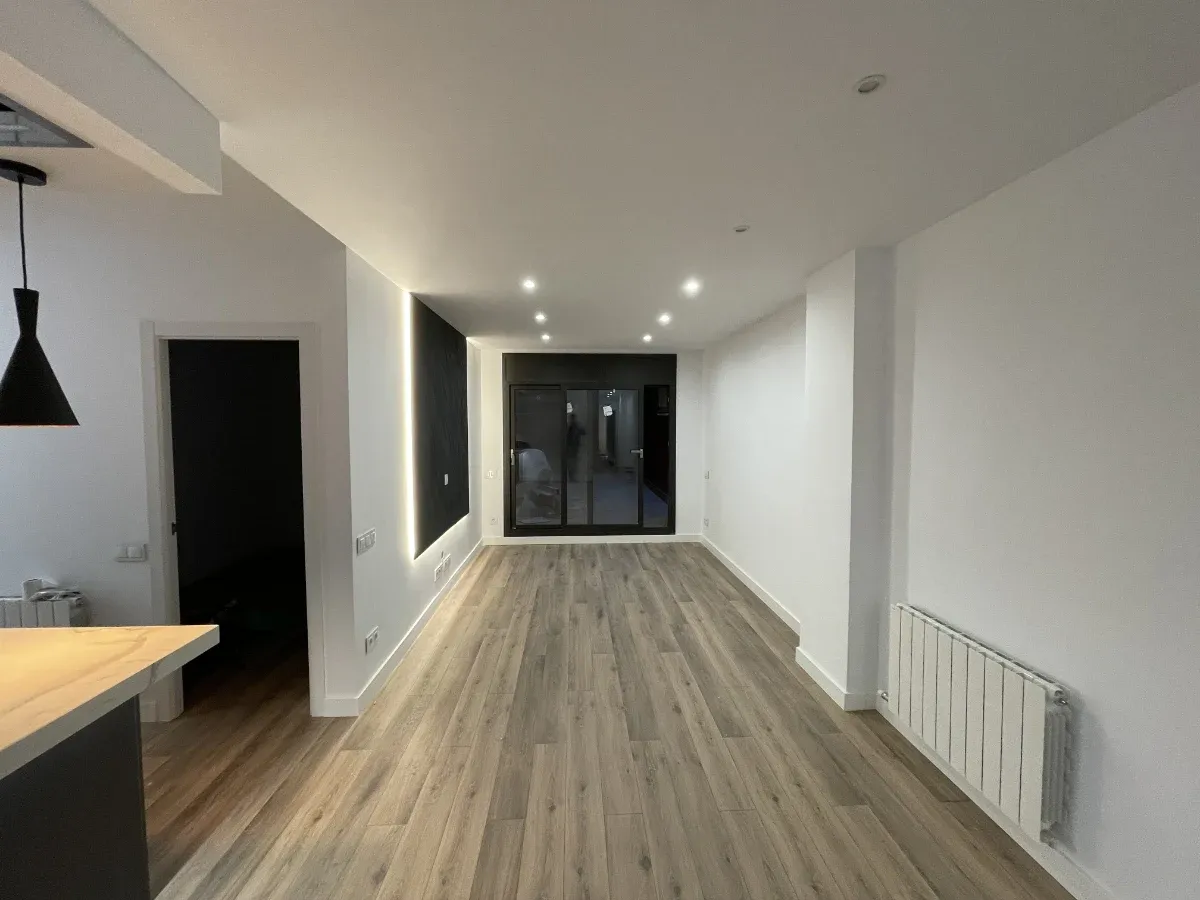 reforma integral de piso en Horta Guinardó, Barcelona - detalle de salón y cocina abierta con salón al fondo e iluminación LED