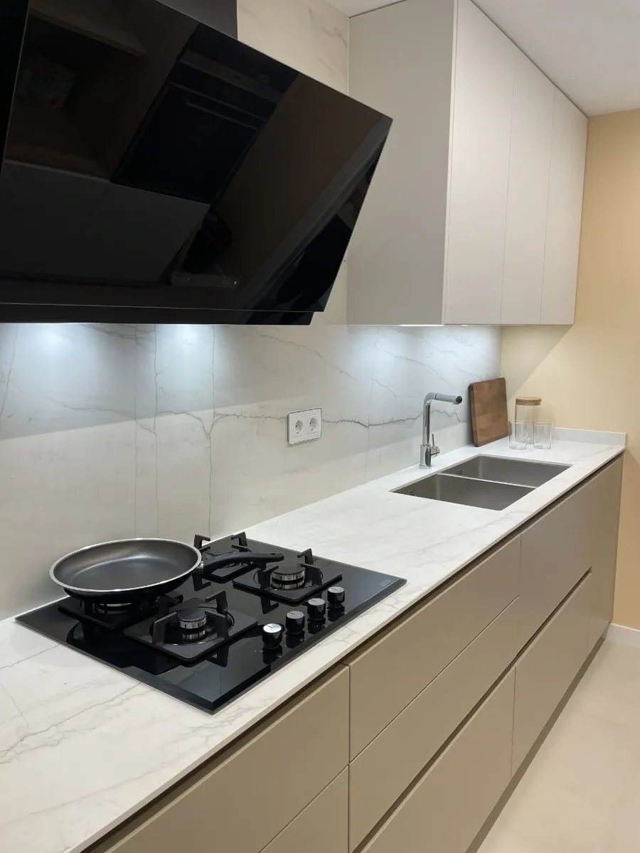Reforma integral de piso en l' Eixample :cocina reformada detalle de fogones campana e iluminación led y fregadero