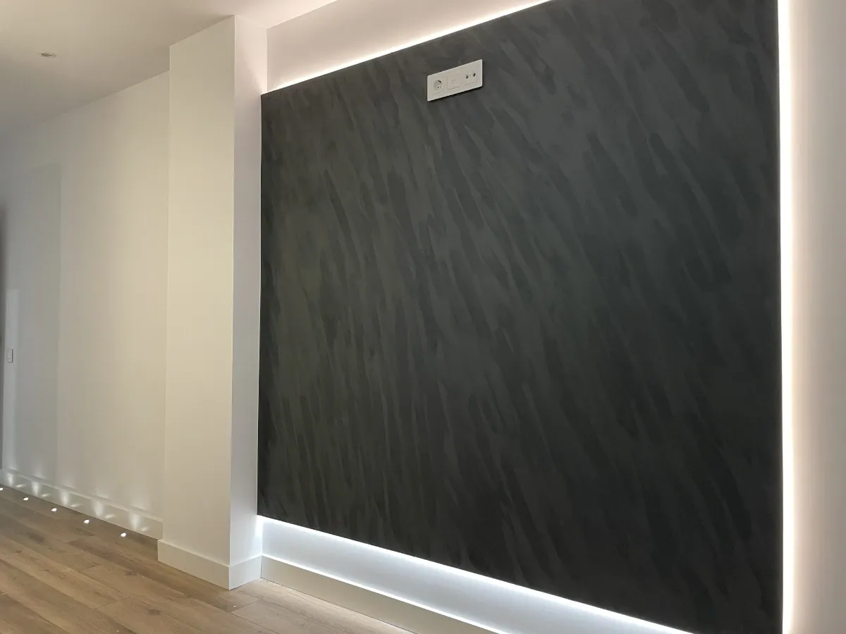 Detalle de panel texturizado negro con retroiluminación LED para pantalla de televisión en nuestro proyecto de reforma llave en mano.