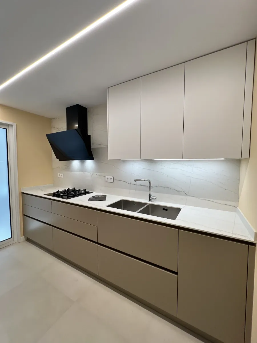Cocina general con muebles superiores: Diseño a medida de muebles de cocina modernos y funcionales en tonos arena y blanco mate sin tiradores.